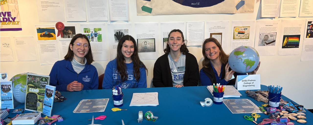 GVSU Outreach team and volunteers at Roger That! leading a sundial activity. Four female employees smiling holding up an inflatable globe.